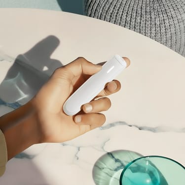 Hand holding a Ploom AURA White Glacier device, a discreet companion always with you