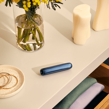 Masanın üzərində yerləşdirilmiş, cihaz üzərində Navy Blue Genişləndirilmiş Naxış Ploom AURA ön panel aksesuarı
