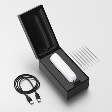 Ploom AURA open box showing the device, its charging cable and cleaning sticks.