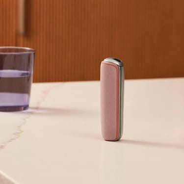 Masanın üzərində dayanan Rose Gold arxa örtüklü Ploom cihazı
