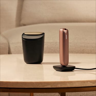 Şarj olunan Ploom AURA cihazının yanında Ploom Böyük Çubuq Qabı