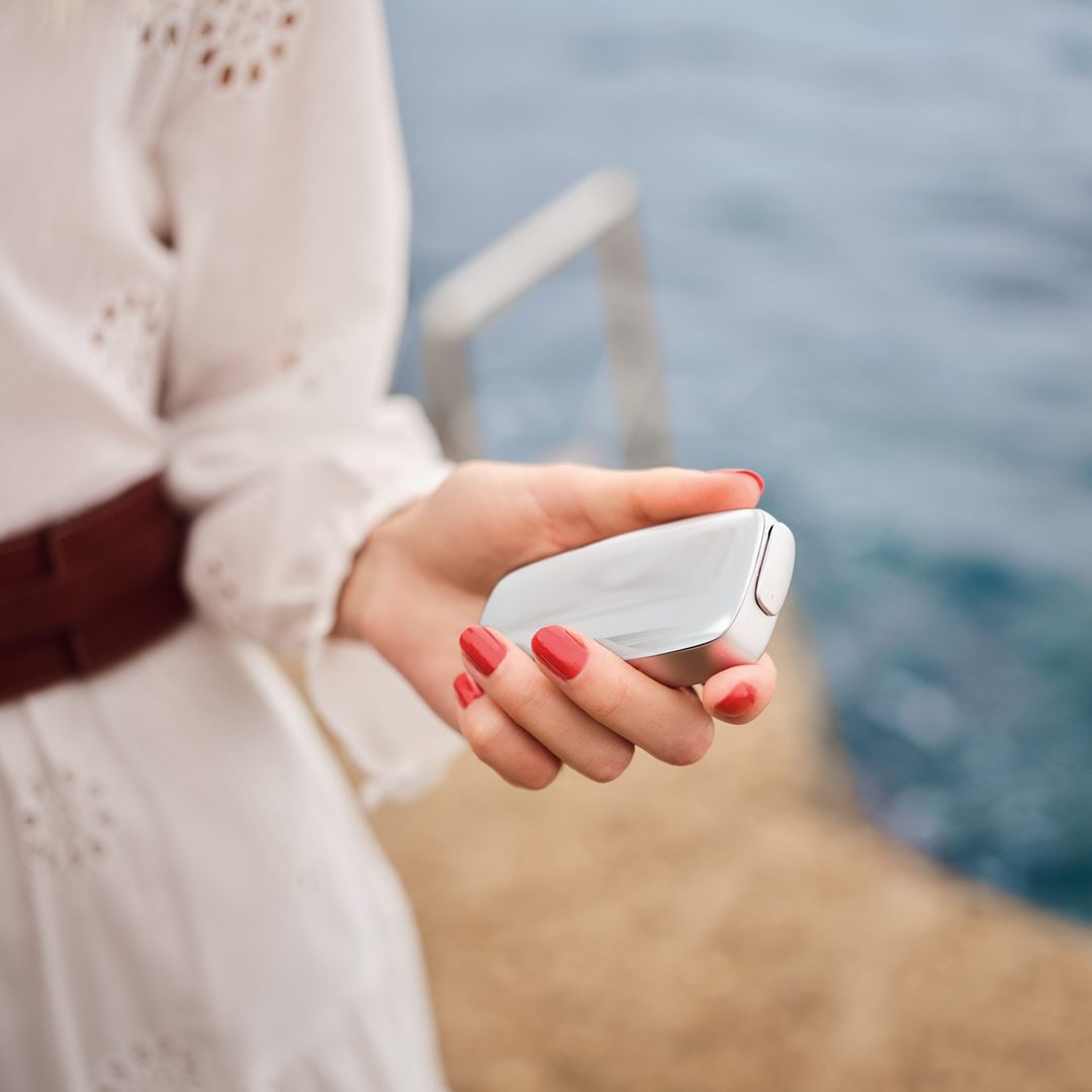 Woman holding Ploom X Advanced with Cotton White front panel in hand, outdoors