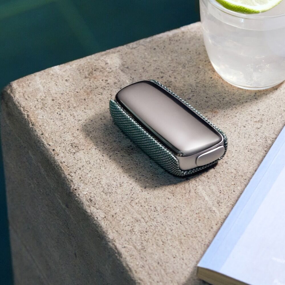 Ploom X Advanced device shown with the fabric Green back cover, poolside with a drink