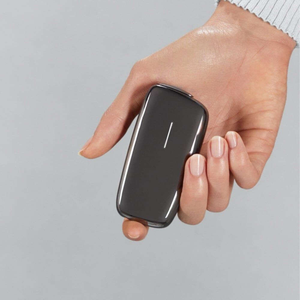 Ploom X Advanced Slate Grey shown in hand, against a grey background
